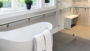 tub in bathroom with separate stand-up shower with silver hand rails t hip-height along the walls